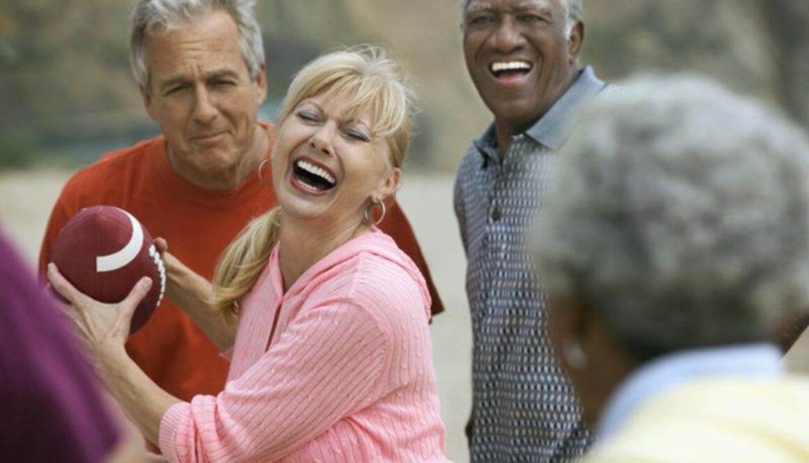 Group of smiling older adults tossing a football outdoors