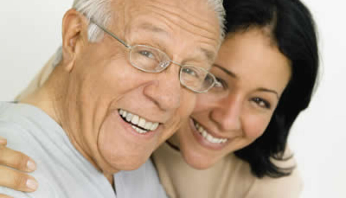 Smiling older man embraced by a younger woman